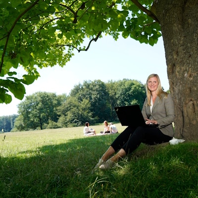 Work-Life-Blending, Flexible Arbeitsmodelle, Frau mit Laptop vor Baum